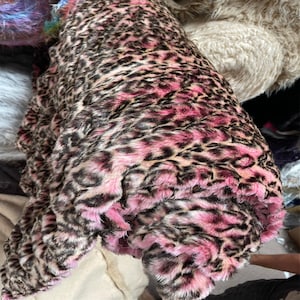 May include: Pink and brown faux fur fabric with a leopard print pattern.