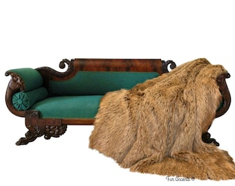 May include: A vintage, dark wood, ornately carved sofa with a teal green velvet cushion and a brown faux fur throw draped over it. The throw is labeled "Fur Accents".