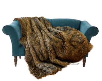 May include: A brown and black faux fur throw blanket draped over a teal blue sofa. The blanket has a long, shaggy pile and is made to look like real fur. The sofa has a classic design with rolled arms and wooden legs.