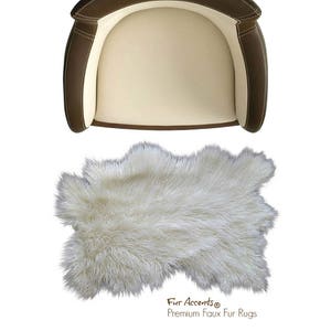 Op de afbeelding: Witte nep-bontkleed met een ruwe textuur. Het kleed is in de vorm van een huid en heeft een bruin label met de tekst "Fur Accents® Premium Faux Fur Rugs".