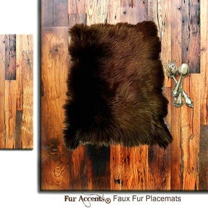 May include: A brown faux fur placemat with a rectangular shape. The placemat is placed on a wooden surface with a rustic design. Silverware, including a fork and spoon, is placed on the wooden surface. The text "Fur Accents® Faux Fur Placemats" is at the bottom.