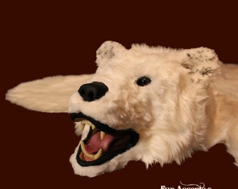 May include: A white polar bear rug with a snarling expression. The rug is made of real fur and has a realistic appearance. The bear's mouth is open, revealing sharp teeth. The rug is a popular choice for home decor and can add a touch of wilderness to any room.