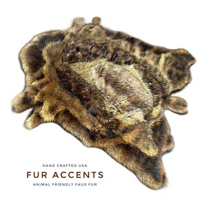 May include: Faux fur rug in shades of brown and tan, with a mottled pattern. The rug is shaped like an animal hide. Text on the image reads "FUR ACCENTS" and "ANIMAL FRIENDLY FAUX FUR".