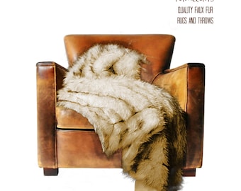May include: A faux fur throw in a light brown color draped over a brown leather armchair. The throw is soft and fluffy, and it would be perfect for adding a touch of luxury to any room. The text "FUR ACCENTS" is visible in the top right corner of the image, along with the text "QUALITY FAUX FUR" and "RUGS AND THROWS".