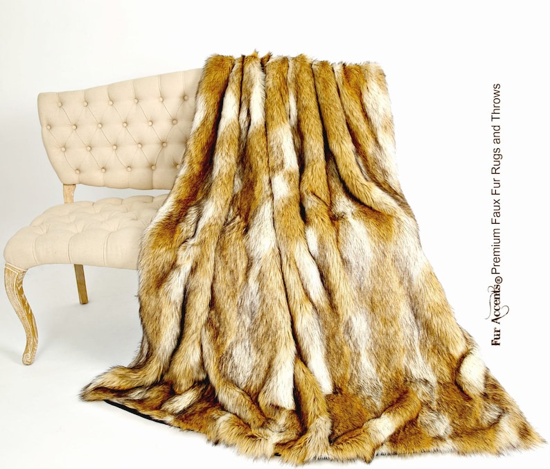 May include: A soft, brown and white faux fur throw blanket draped over a white tufted bench. The blanket has a long, shaggy pile and is perfect for adding warmth and texture to any room.