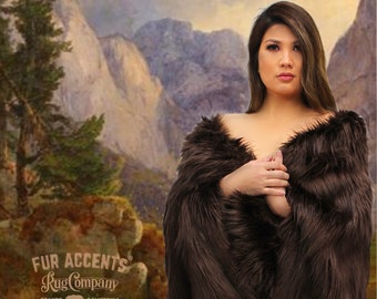 May include: A woman wearing a brown faux fur shawl in front of a painting of mountains. The text "FUR ACCENTS Rug Company ORANGE CALIFORNIA" is visible in the bottom left corner of the image.