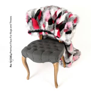 May include: A gray tufted chair with wooden legs is topped with a faux fur throw in shades of pink, black, and white.