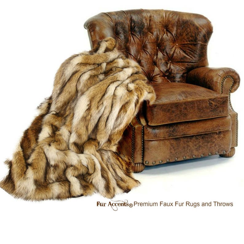 May include: A brown faux fur throw draped over a brown leather armchair with tufted upholstery. The throw has a long, shaggy pile and a striped pattern.