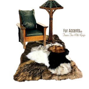May include: A faux fur pelt rug with brown, black, and white fur sections. The rug is laid out on a white background with a wooden chair and a lamp in the background. The text "Fur Accents® Faux Fur Pelt Rugs" is visible in the upper right corner of the image.