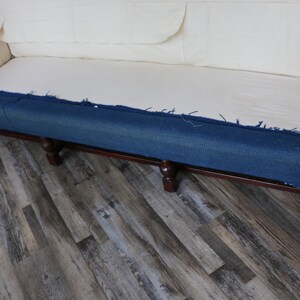 May include: A close-up of a sofa with a blue denim fabric covering the bottom of the frame. The sofa is sitting on a wood floor.