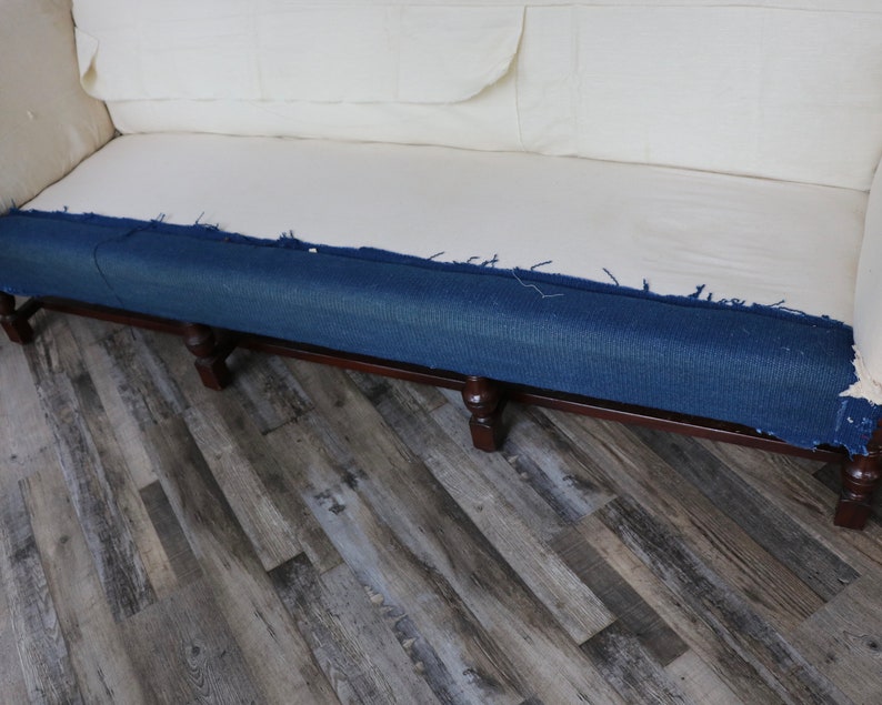 May include: A close-up of a sofa with a blue denim fabric covering the bottom of the frame. The sofa is sitting on a wood floor.