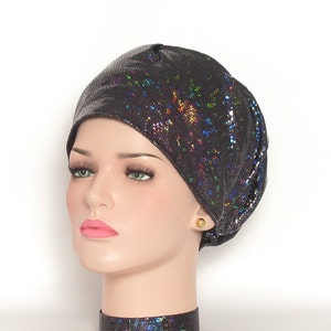 May include: A black, iridescent, textured beanie hat. The hat has a snakeskin-like pattern with a shimmering, multi-colored effect. The hat is shown on a mannequin head with a gold stud earring.