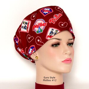 May include: Burgundy Euro style Phillies #12 cap with a repeating pattern of Phillies logos and baseball-themed graphics. The cap is made of a soft fabric and is designed to fit comfortably. The cap is displayed on a mannequin head.