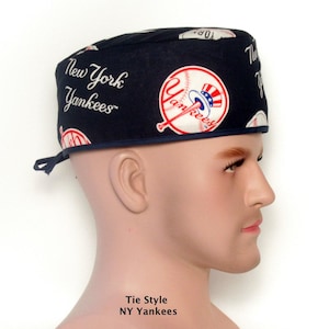 May include: A navy blue tie-style cap featuring the New York Yankees logo and team name. The cap has a baseball design with red, white, and blue accents. The text "New York Yankees" is printed on the cap.