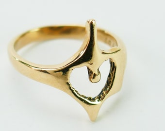 May include: A gold ring with a heart-shaped cutout in the center. The ring is made of a smooth, shiny metal and has a simple, elegant design.