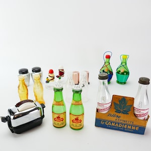 Pode incluir: Uma coleção de saleiros e pimenteiros em miniatura com a forma de várias garrafas, incluindo garrafas de cerveja, garrafas de vinho e garrafas de refrigerante. Há também uma torradeira em miniatura e uma caixa de cerveja canadense.