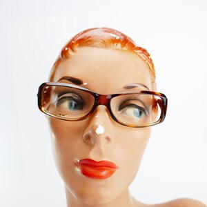 Peut inclure: Une t&ecirc;te de mannequin avec des cheveux roux portant des lunettes en &eacute;caille de tortue brunes.