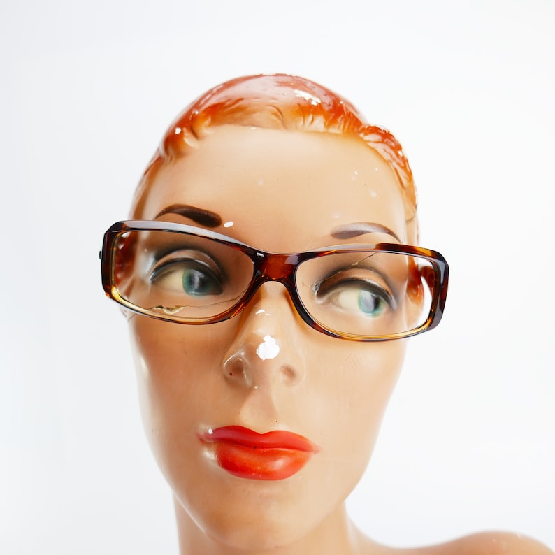 Peut inclure: Une t&ecirc;te de mannequin avec des cheveux roux portant des lunettes en &eacute;caille de tortue brunes.