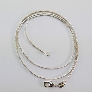 Op de afbeelding: Een zilveren slangenketting met een karabijn sluiting.