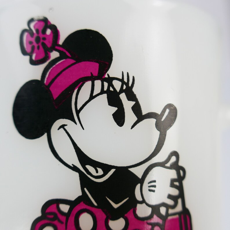 May include: Close-up of a white surface with a graphic of Minnie Mouse. The cartoon character is depicted in black and white with a pink bow and polka-dotted dress. The image is a classic Disney design.