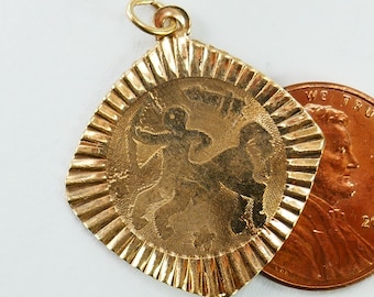 Puede incluir: Pendiente de encanto de tono dorado con una imagen detallada de un centauro, una criatura mítica con la parte superior del cuerpo de un humano y la parte inferior del cuerpo de un caballo. El pendiente es de forma cuadrada con un borde texturizado y tiene aproximadamente el tamaño de una moneda de un centavo de euro.