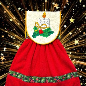May include: A red kitchen towel with a decorative top featuring a candle, holly, and a yellow bow. The bottom of the towel has a green and red holly border. The towel is designed for the Christmas holiday season.