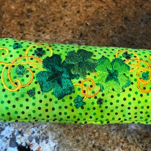 May include: Green pot holder with a polka dot pattern and embroidered shamrocks and swirls.
