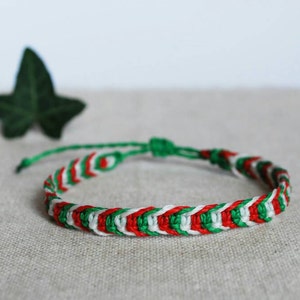 Op de afbeelding: Een groene, witte en rode vriendschapsarmband met een chevron-patroon.