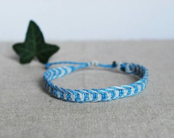 Op de afbeelding: Een blauw en wit gestreept vriendschapsarmband gemaakt van gevlochten touw.