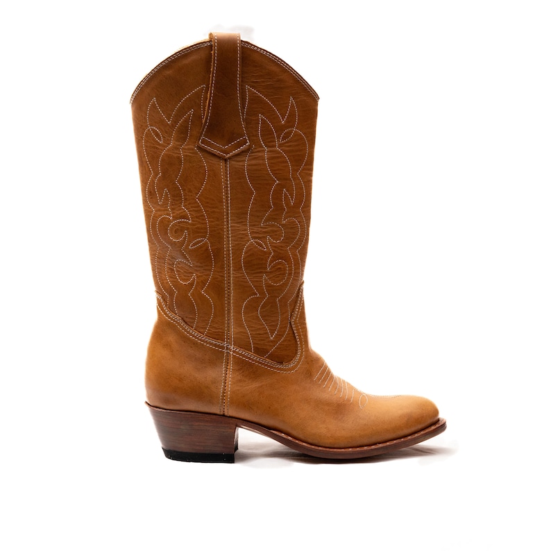 May include: A pair of brown leather cowboy boots with white stitching. The boots have a pointed toe and a low heel.