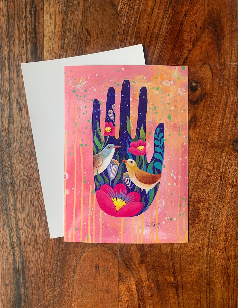 May include: A pink and blue hand with flowers and birds. The hand is painted in a whimsical style with bright colors and details. The birds are perched on the flowers and are looking at each other.