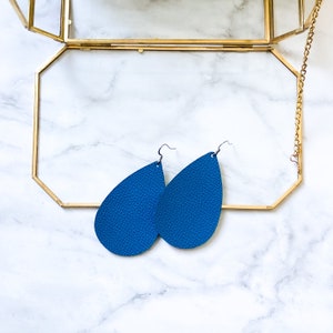 May include: A pair of teardrop-shaped blue leather earrings with silver hooks.