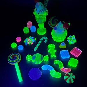Può includere: Una collezione di repliche di caramelle in vetro che brillano sotto la luce UV, tra cui una coppa gelato, un cupcake, un lecca-lecca, un bastoncino di zucchero, orsetti gommosi, vermi e varie caramelle. Una moneta da 25 cent è inclusa.