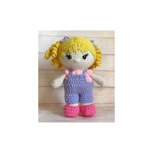 May include: A crocheted doll with yellow hair, a pink and white shirt, blue overalls, and pink shoes.