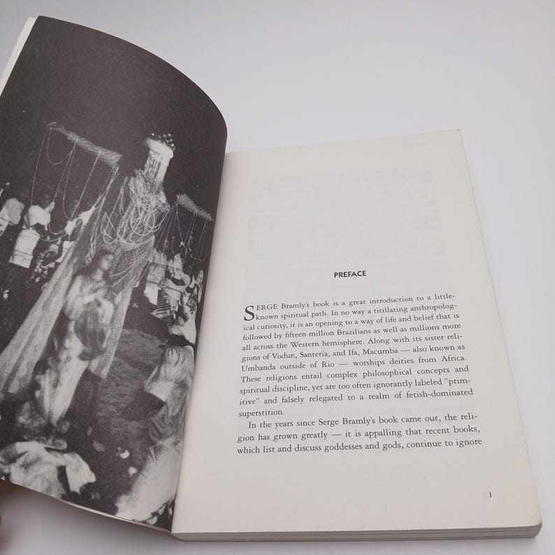 Puede incluir: Un libro abierto con una fotograf&iacute;a en blanco y negro en la p&aacute;gina izquierda que muestra figuras con vestimenta ceremonial. La p&aacute;gina derecha presenta el t&iacute;tulo PREFACE seguido de un texto que comienza con la letra S sobre religiones.