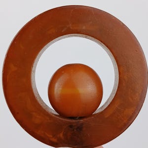 May include: A vintage brown pendant featuring a large circular frame with a smaller sphere nestled inside. The pendant has a marbled appearance and a glossy finish. The design is simple and elegant, suitable for various styles.