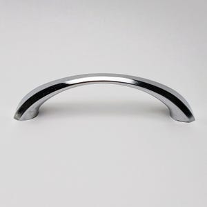 Könnte beinhalten: Ein polierter Chrom-Möbelgriff mit einem glatten, bogenförmigen, halbkreisförmigen Design. Das Beschlagteil verfügt über eine reflektierende, metallisch silberne Oberfläche mit nach unten gebogenen Enden für den Einsatz an Möbeln.