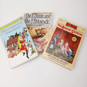 May include: Three vintage children's books are displayed. "Pippi Longstocking" by Astrid Lindgren, features a girl climbing a ladder. "The Mouse and the Motorcycle" shows a mouse and motorcycle. "The Boxcar Children" depicts children near a boxcar.