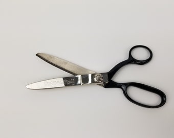 May include: Black handled fabric shears with a silver blade. The blade is serrated and the shears are labeled "WISS Made in U.S.A."