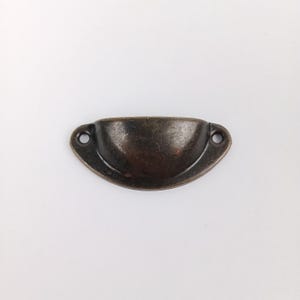 May include: A half-round, antique brass cabinet pull with two small holes for mounting.