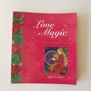 Puede incluir: Un libro rosa titulado Love Magic: Potions, Rituals, and Spells to Attract Love into Your Life de Sally Morningstar. La portada presenta un borde vertical de rosas rojas, contornos de corazones blancos y una ilustración de una persona tocando el arpa.