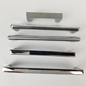 Op de afbeelding: Vijf verschillende zilveren kastgrepen, waaronder een rechthoekige greep, een afgeronde staafgreep en een vierkante greep met een afgeronde bovenkant.