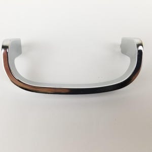 May include: A silver-toned, curved cabinet pull with a smooth, rounded edge.
