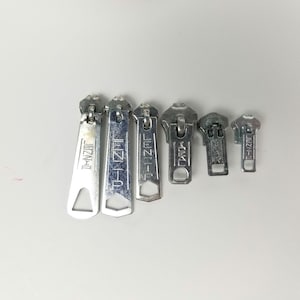 May include: Six silver zipper pulls with the brand name "LENZIP" printed on them.