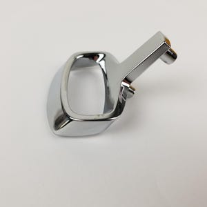 Op de afbeelding: Een verchroomd metalen handvat met een vierkante lus en een kleine, gehoekte hendel. Het handvat is ontworpen om te trekken of te tillen.