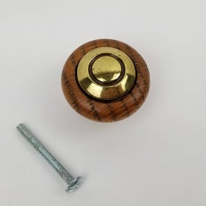 May include: A wooden knob with a brass center, featuring a concentric circle design. The knob comes with a silver screw.