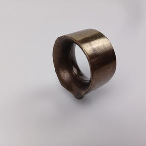 May include: A brass ring with a circular opening, designed for hanging curtains or drapes.