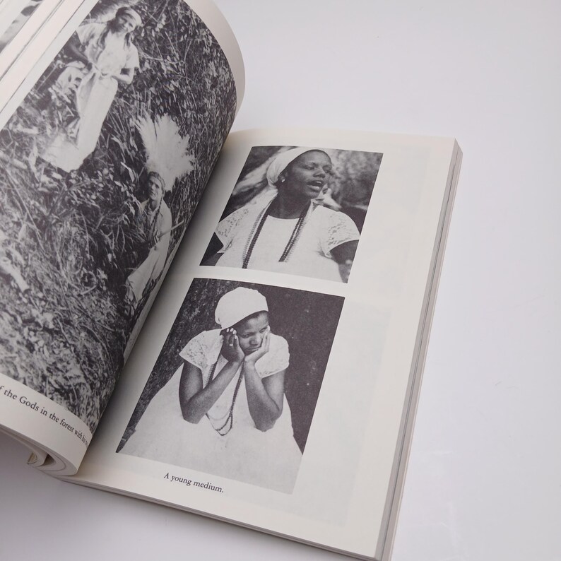 Puede incluir: Un libro impreso en blanco y negro abierto en p&aacute;ginas con fotograf&iacute;as de personas con ropa blanca y tocados. Una imagen muestra a una persona con las manos en la cara, con el pie de foto A young medium, y otra muestra a una persona cantando.