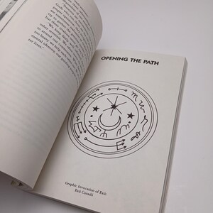Puede incluir: Un libro abierto con p&aacute;ginas de color blanco roto, texto negro y un dise&ntilde;o gr&aacute;fico circular. El texto en la parte superior dice OPENING THE PATH, y el texto en la parte inferior dice Graphic Invocation of Ex&uacute;: Ex&uacute; Curad&oacute;. El gr&aacute;fico es un c&iacute;rculo.