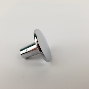 May include: A chrome-plated knob with a round, flat top and a cylindrical base. The knob is designed for use on furniture or cabinets.